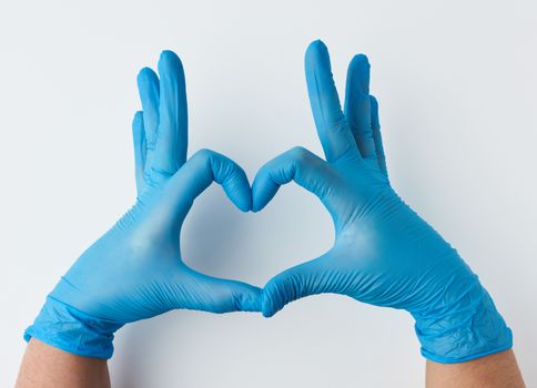two hands in blue latex sterile medical gloves shows a gesture of the heart on a white background, concept of goodness, help and volunteering