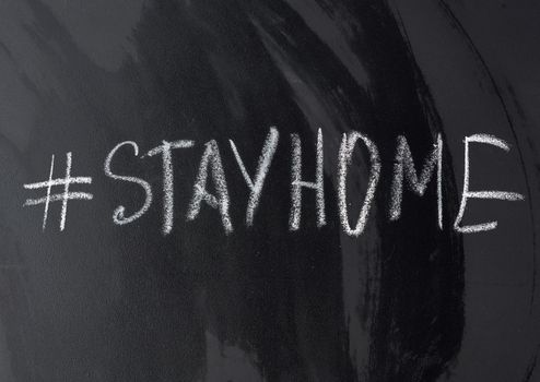 inscription stay home in chalk with a hashtag on a black chalk board, concept of self-isolation in an epidemic and pandemic