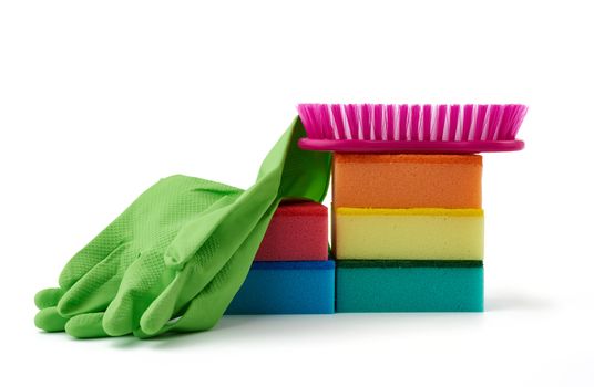 items for home cleaning: green rubber gloves, brush, multi-colored sponges for dusting on a white background