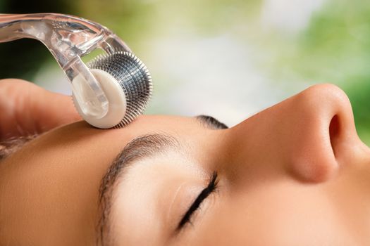 Macro close up portrait of woman having beauty skin treatment.Therapist preparing skin with derma roller.