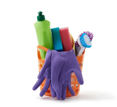 orange basket with washing sponges, rubber protective gloves, brushes and cleaning agent in a green plastic bottle, set isolated on a white background