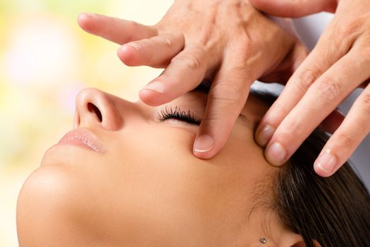 Extreme close up portrait of woman having beauty facial treatment. Therapist doing massage with product on cheek.