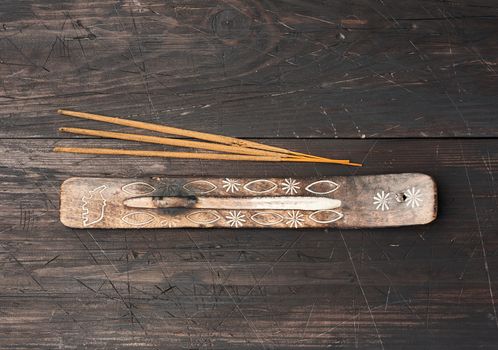 stack of incense sticks for rituals and a stand on a brown wooden table, top view