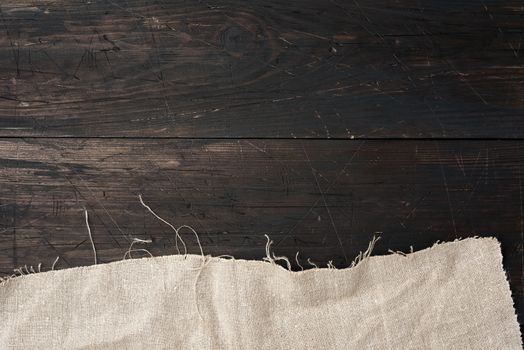 gray kitchen textile towel folded on a brown wooden table from old boards, top view, empty space. Rustic texture. Retro background