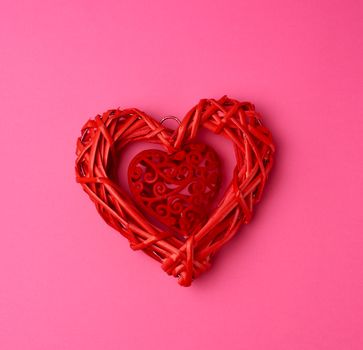 red wicker decorative heart on a pink background, festive backdrop, top view