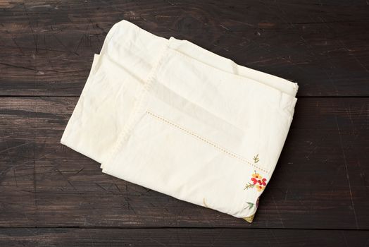 beige kitchen textile towel folded on a gray wooden table from old boards, top view, empty space. Rustic texture. Retro background