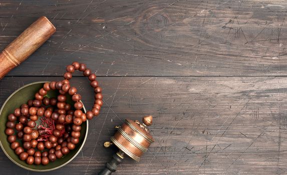 Tibetan singing copper bowl with a wooden clapper on a brown wooden table, objects for meditation and alternative medicine, top view, copy space