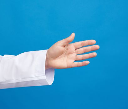 medic in a white coat pulls his hand for a handshake on a blue background, close up