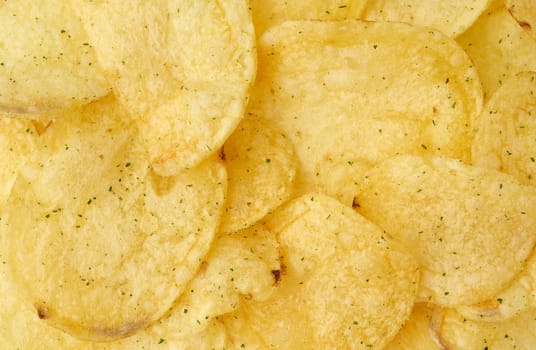 heap of round yellow fried potato chips with dill, food with spice, top view