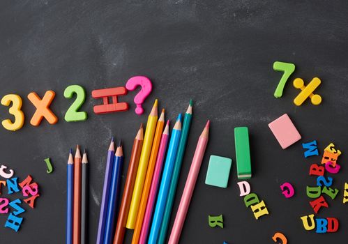 wooden multi-colored pencils, plastic numbers on a black background, concept back to school, copy space