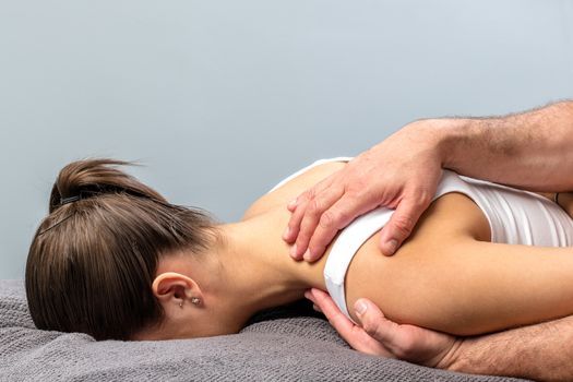 Close up of detail of woman having physical shoulder treatment.Male therapist hands manipulating scapula.