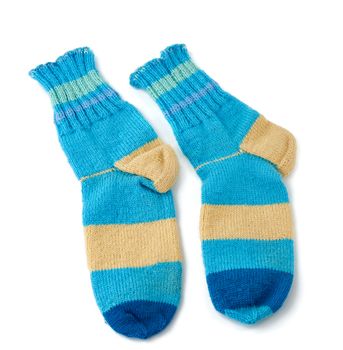 pair of striped handmade knitted warm socks made of sheep’s wool yarn, blue clothing is isolated on a white background