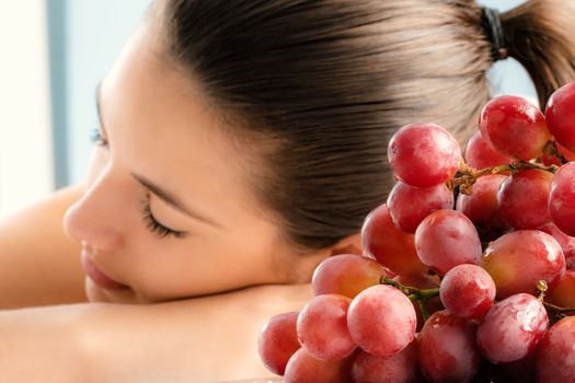 Close up bunch of red grapes with girl in background.Girl having aromatherapy in wine spa.