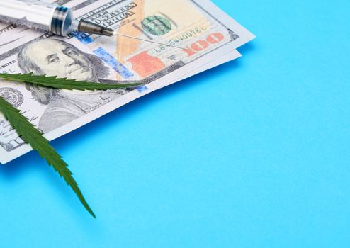 cash US dollars, green hemp leaf and empty plastic syringe, drug addiction concept
