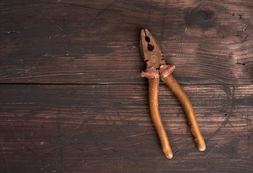 old vintage pliers on a brown wooden background, close up, copy space