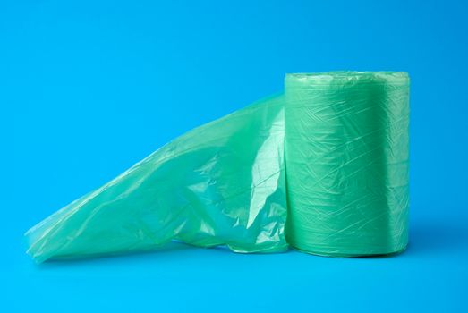 roll green plastic bags for trash bin on blue background, close up