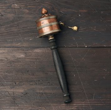 copper Tibetan prayer drum on a brown wooden background, top view