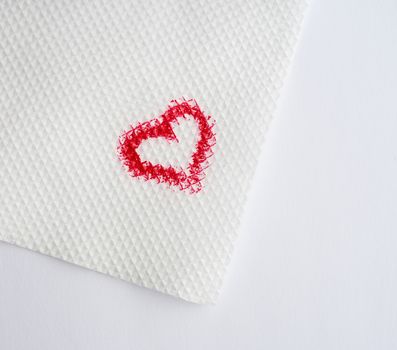 painted heart with red lipstick on a white paper napkin, close up