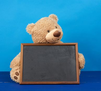 brown teddy bear and empty wooden rectangular frame, chalk board for writing a to-do list. Back to school