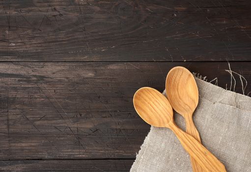 two empty wooden spoons on a brown wooden background from boards, top view, copy space