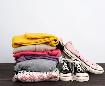 stack of various folded clothes and textile worn cedwas on a wooden table, white background, concept for helping the needy and poor, volunteering
