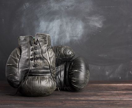 black leather vintage boxing gloves on a black background, sports equipment, copy space