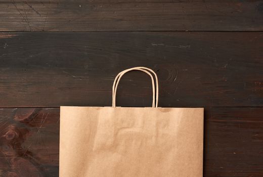 brown paper bag for food packaging on a brown wooden background, concept of rejection of plastic bags to save the environment, top view