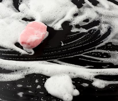 white soap foam and pink soap on a black background, top view, concept of cleanliness, antibacterial, close up