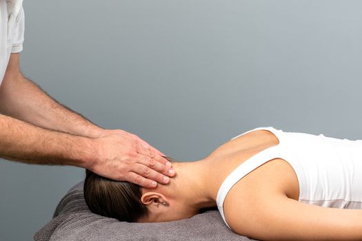 Close up of osteopath doing manipulative neck and head massage on female patient.