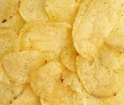 heap of round yellow fried potato chips with dill, food with spice, top view