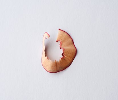 wooden shavings from red cosmetic lip liner on a white background, close up