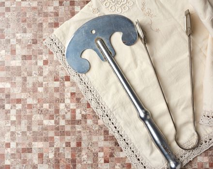 vintage iron knife and tongs on a beige kitchen towel, top view