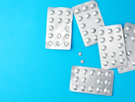 round pills in blister packs on a blue background, copy space