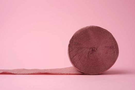 untwisted roll of pink toilet paper on a pink background, close up