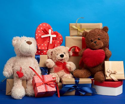 bunch of gifts in boxes tied with silk ribbons and soft teddy bears on a blue background, festive backdrop for birthday, Christmas