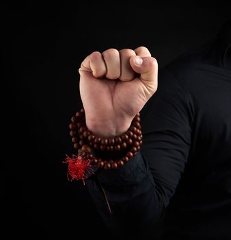 hand of an adult male shows Mushti Mudra on a dark background, clenched fist