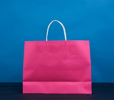 pink paper bag with a handle for shopping and gifts on a blue background, close up