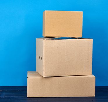 stack of cardboard boxes of brown kraft paper on a blue wooden table, moving concept