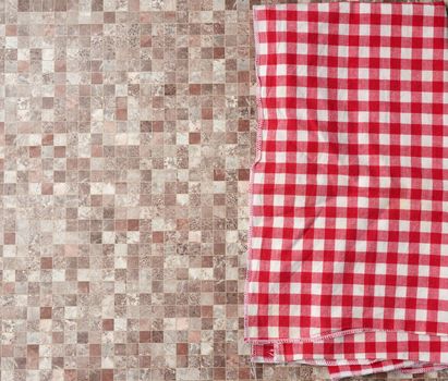 red checked cotton kitchen towel on a brown kitchen surface, top view, copy space