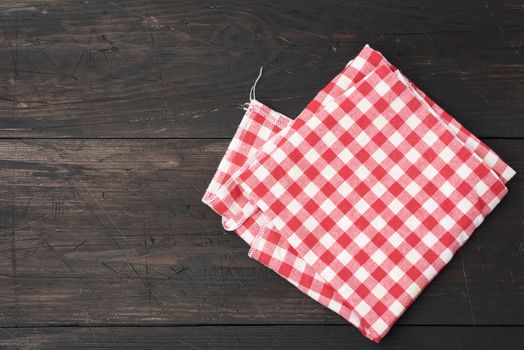 red-white textile kitchen towel on a brown wooden background from old boards, top view