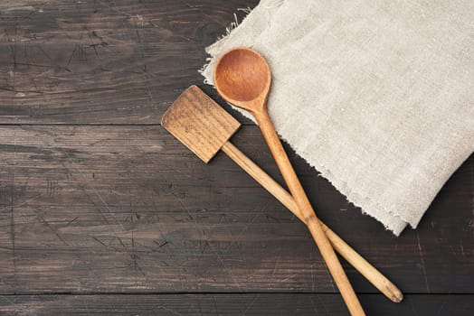 empty wooden spoon and spatula on a brown wooden background from boards, top view, copy space