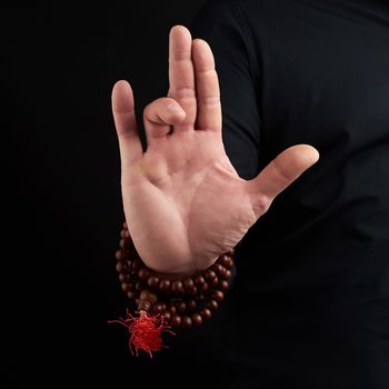 hand of an adult male shows mudra on a dark background, close up