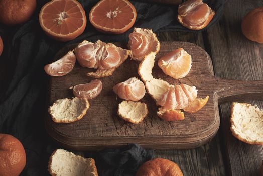 ripe round tangerines and cut in half on an old vintage cutting board. Healthy vegetarian food. Citrus fruit, top view