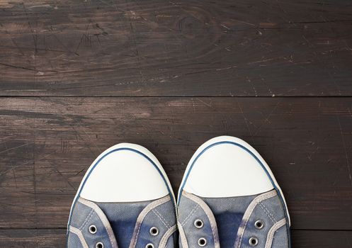 blue men's old  sneakers on a brown wooden surface, top view, empty space