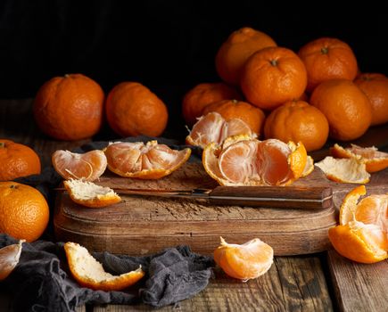 ripe round tangerines and cut in half on an old vintage cutting board. Healthy vegetarian food. Citrus fruit, top view