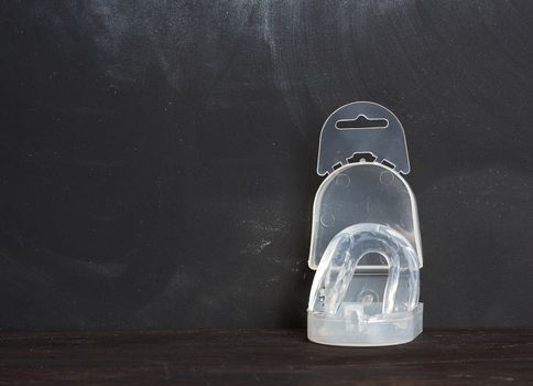 transparent silicone mouth guard for protection during sports competitions on a black background, place for inscription