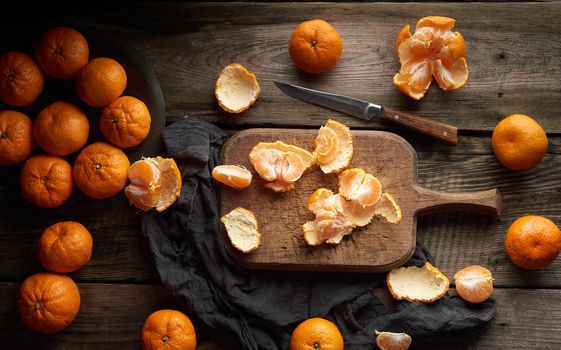 ripe round tangerines and cut in half on an old vintage cutting board. Healthy vegetarian food. Citrus fruit, top view