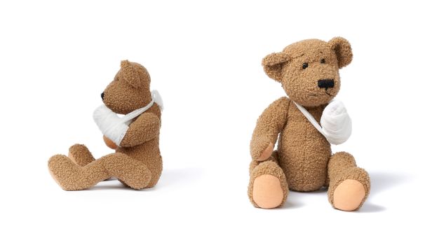 funny vintage brown curly teddy bear with rewound paw with white gauze bandage isolated on white background, concept of injuries in children or animals, set