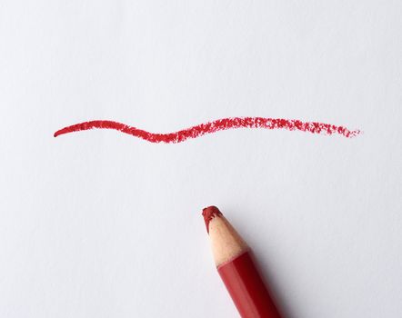 wooden red cosmetic lip liner and sample on a white background, close up