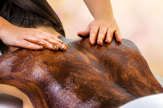 Close up detail of hands doing back massage on woman. Therapist using hot antioxidant chocolate wax on body.
